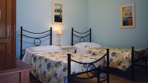 A bedroom with two single beds, a nightstand, a lamp, and two framed pictures on the wall. - Torre Clementina (Fiumicino)