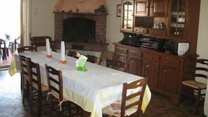 A dining area with a table set for four, wooden chairs, a fireplace, and a wooden cabinet with glass doors. - Torre Clementina (Fiumicino)