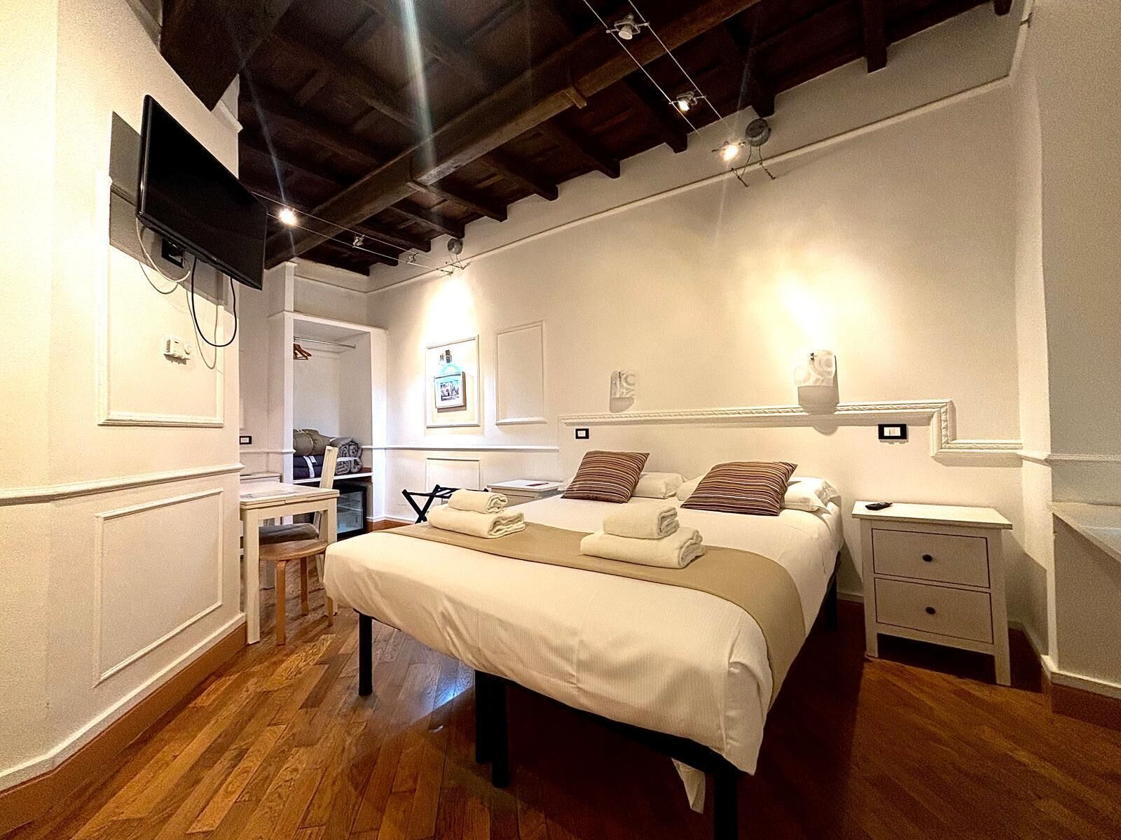 A hotel room with a bed, bedside tables, a desk, and a chair.