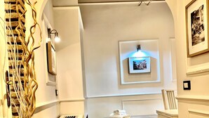 A narrow hallway with wooden flooring, a white radiator, a small table with a folded towel, and a framed picture on the wall. - Domus Ester Roma (Rome)