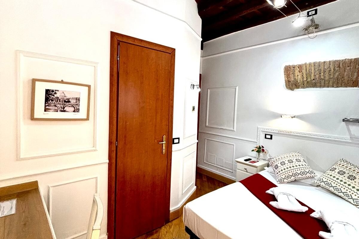 A bedroom with a wooden ceiling, a bed with white bedding, a nightstand, and a framed picture on the wall.