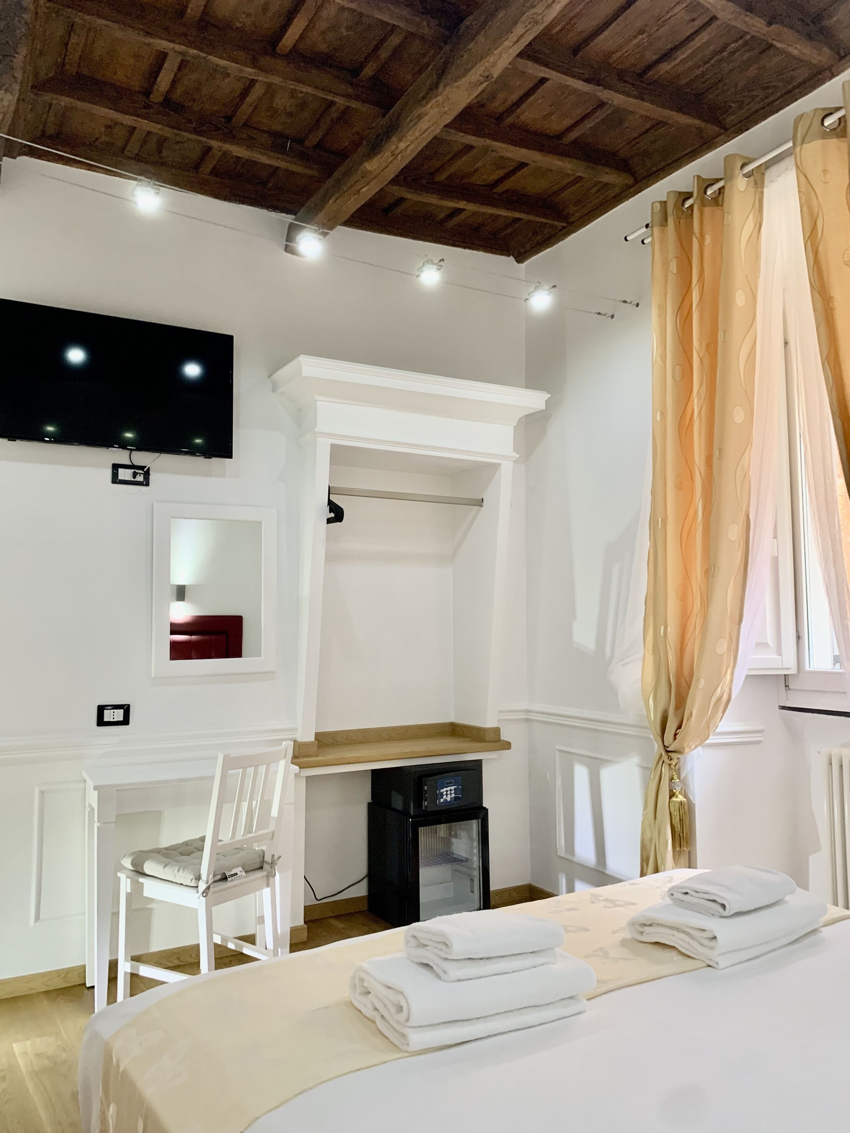 Ein Hotelzimmer mit Bett, Schreibtisch, Sessel, Fernseher und Heizkörper.