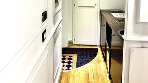 A narrow hallway with white walls, a wooden floor, and a tiled backsplash in the kitchen area. - Domus Ester Roma (Rome)