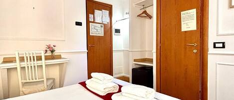 Habitación de hotel con una cama grande, un escritorio de madera, una silla y dos puertas.