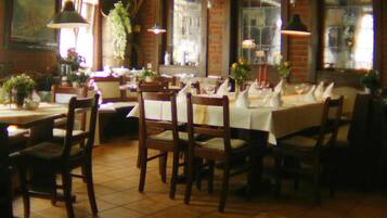Un restaurante con paredes de ladrillo, sillas y mesas de madera dispuestas para comer.