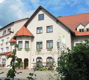 Il s’agit d’un bâtiment traditionnel, doté d’un toit à pignon, de nombreuses fenêtres et d’une enseigne indiquant qu’il s’agit d’un hôtel.