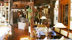 A rustic dining area with wooden beams, tables set for dining, and hanging decorations. - Hotel-Gasthof am Selteltor (Wiesensteig)