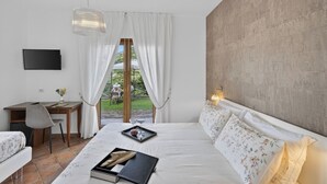 Een slaapkamer met een bed, een bureau, een stoel, een televisie en uitzicht op de omgeving.