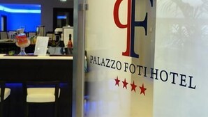 Un cartel de hotel con el nombre 'Palazzo Foti Hotel' y tres estrellas.
