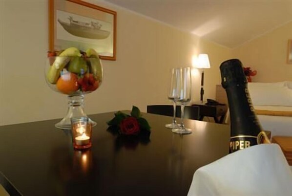 A hotel room with a dining table set with a fruit bowl, candles, and wine glasses.