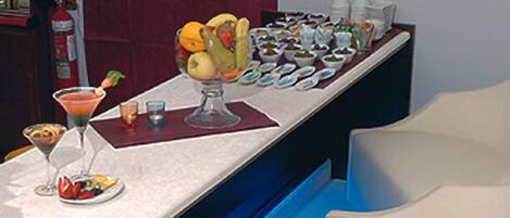 A bar area with a variety of drinks and a fruit bowl.