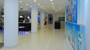 Un lobby espacioso con techos altos, grandes columnas blancas y un piso pulido.