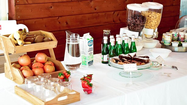 Una mesa de buffet con diversos alimentos, como manzanas, fresas y una variedad de bebidas.