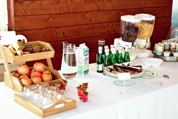 A buffet table with various food items, including apples, strawberries, and a variety of beverages. - Lebbiano Residence Bio Resort  (Scandicci)