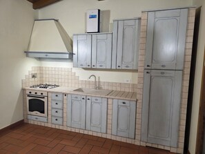 Una cocina compacta con estufa a gas, pileta y alacenas.