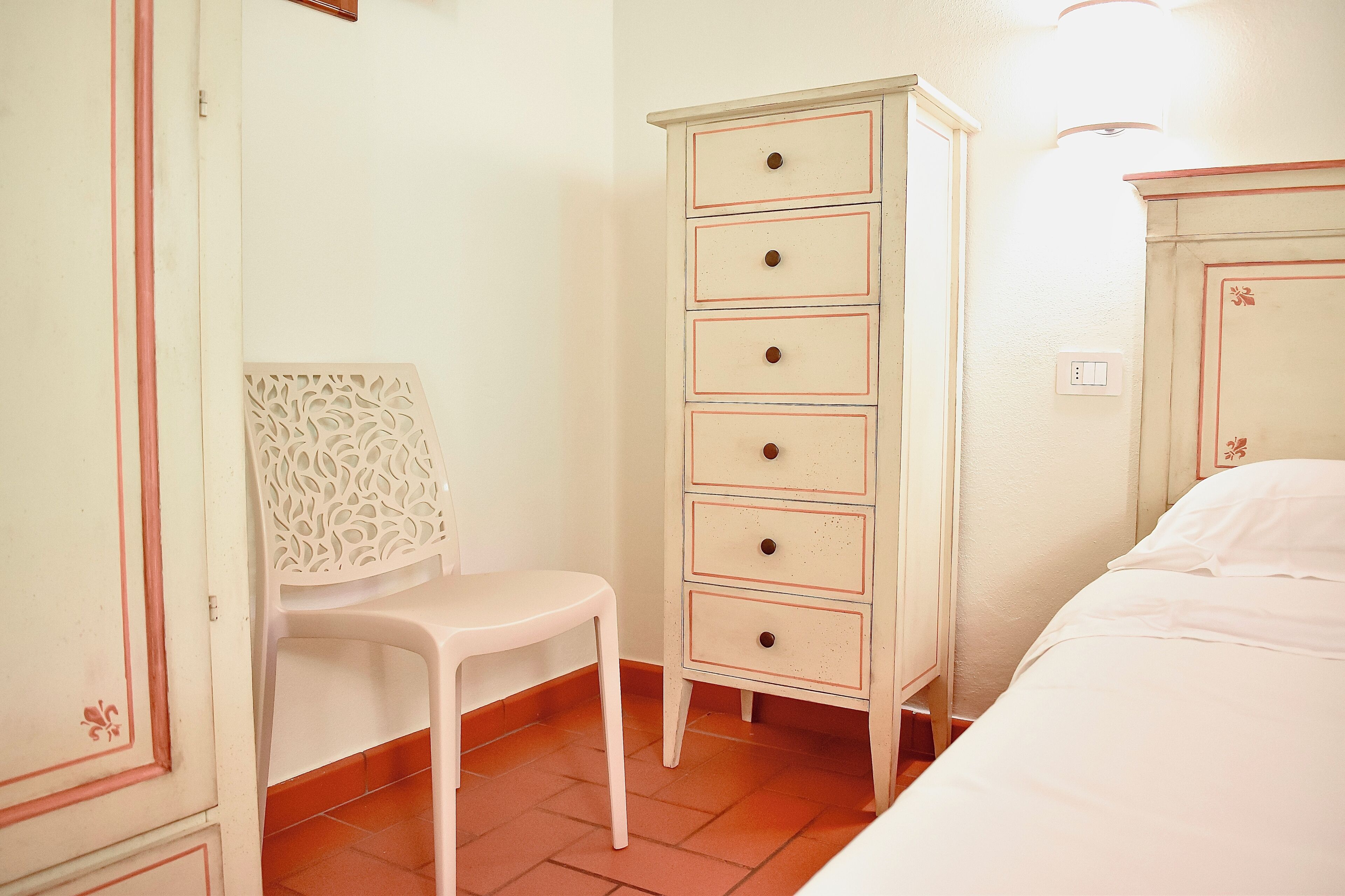 Un dormitorio con cama, cómoda blanca con cajones y una silla.