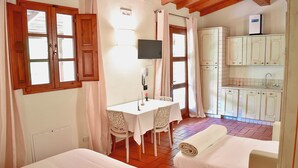 Una habitación con una cama, una mesa con sillas, un televisor y una kitchenette.