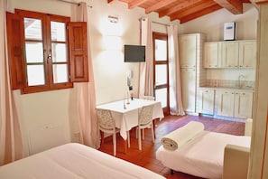 Una habitación con una cama, una mesa con sillas, un televisor y una kitchenette.