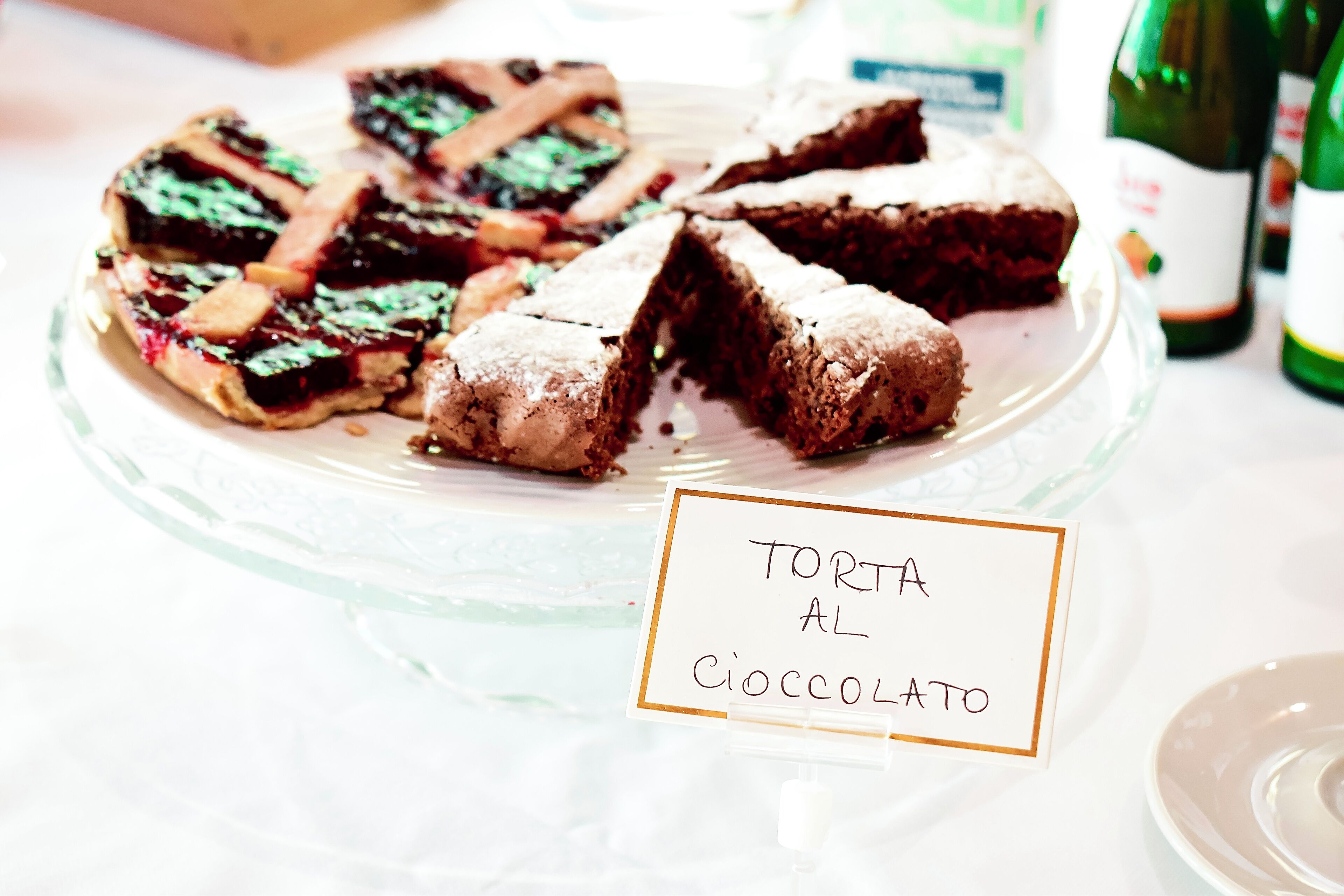 Une assiette de desserts comprenant une tarte et des brownies au chocolat, avec l’inscription « TORTA AL COCCOLATO ».