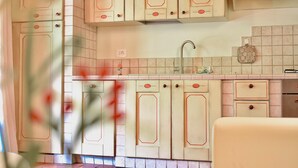Una cocina con gabinetes de color claro, un fregadero de acero inoxidable y un salpicadero de azulejos.