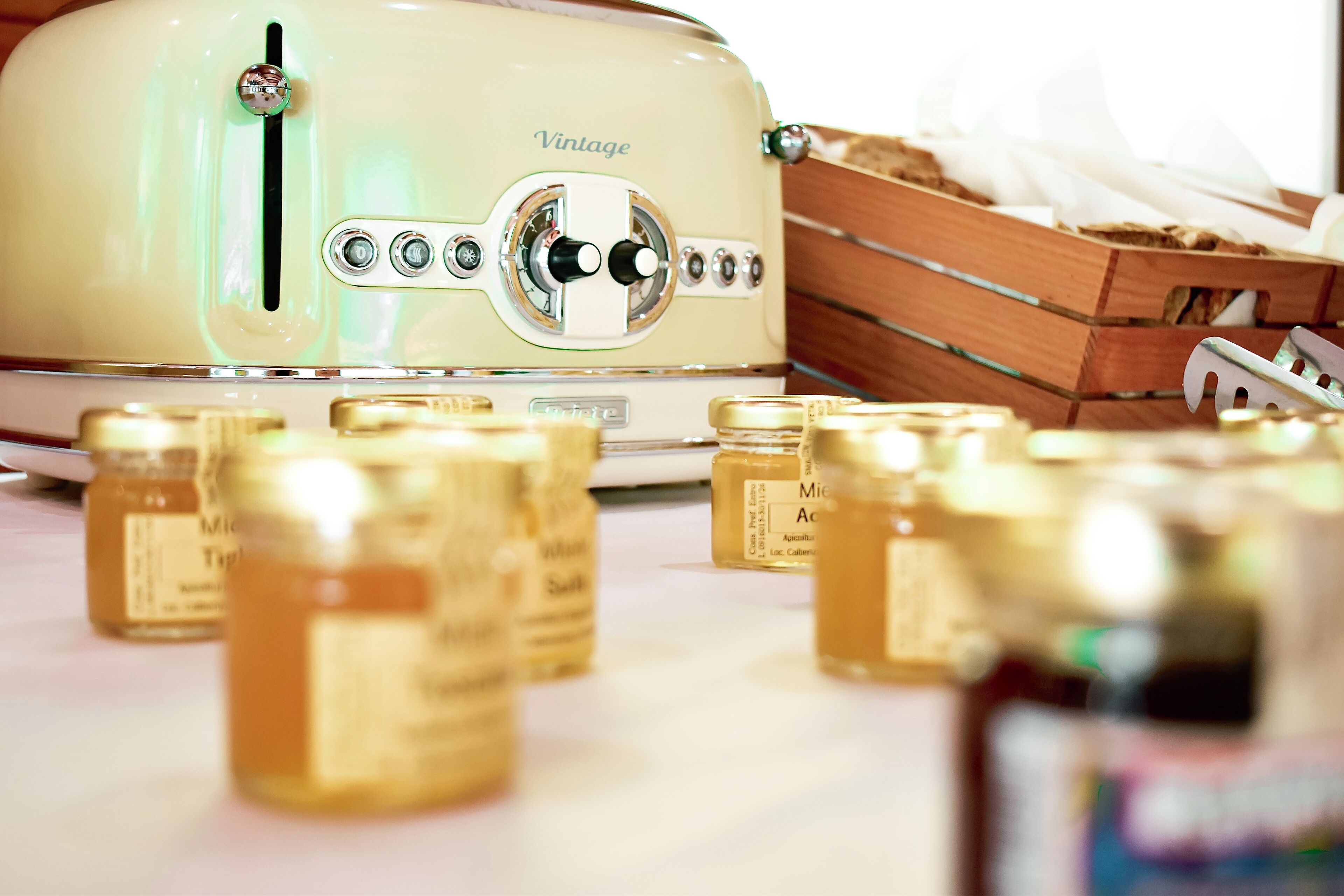A vintage toaster with jars of honey in front of it.