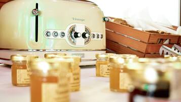 A vintage toaster with jars of honey in front of it.