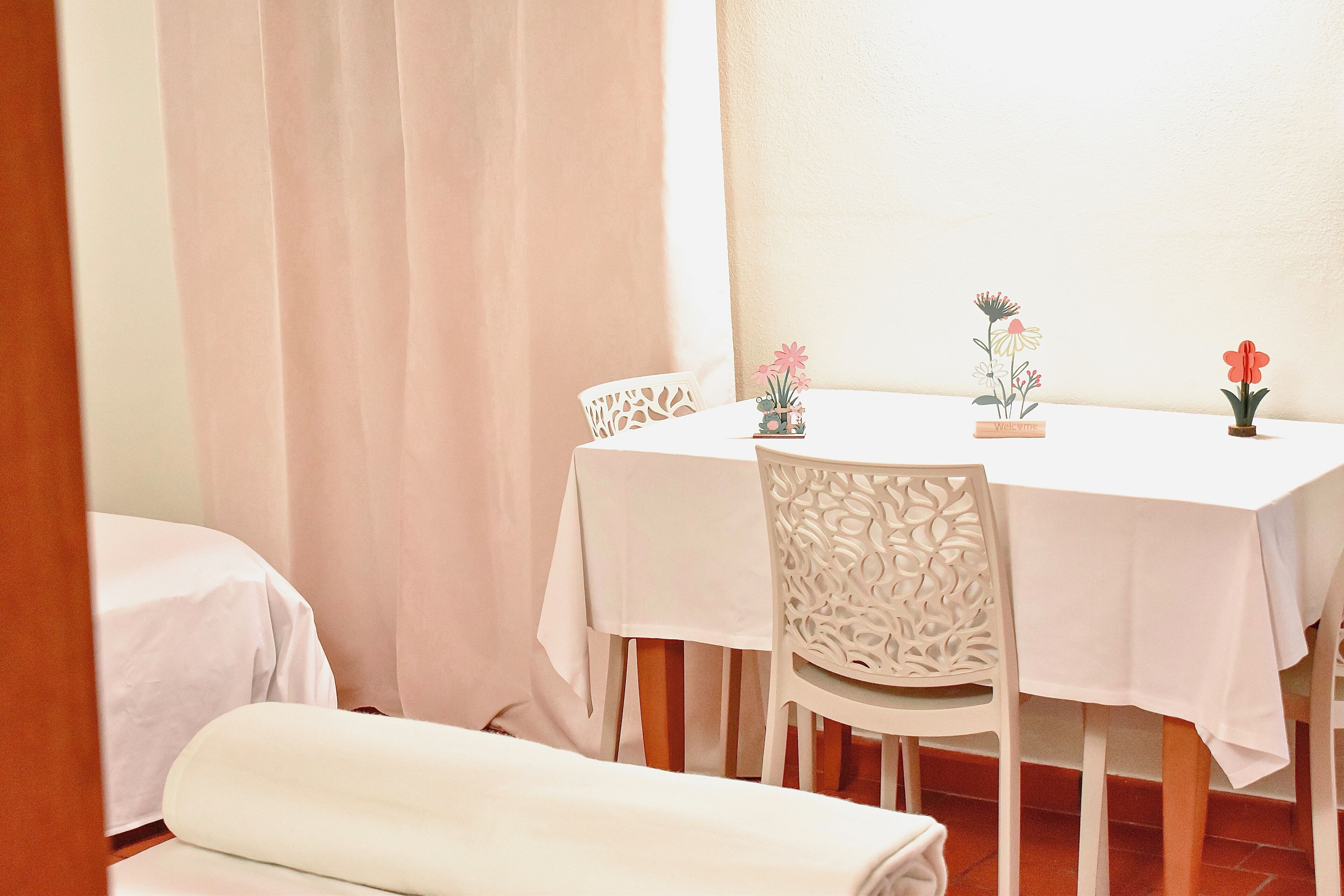 Un comedor con una mesa y sillas, una planta pequeña en maceta, y una cama al fondo.