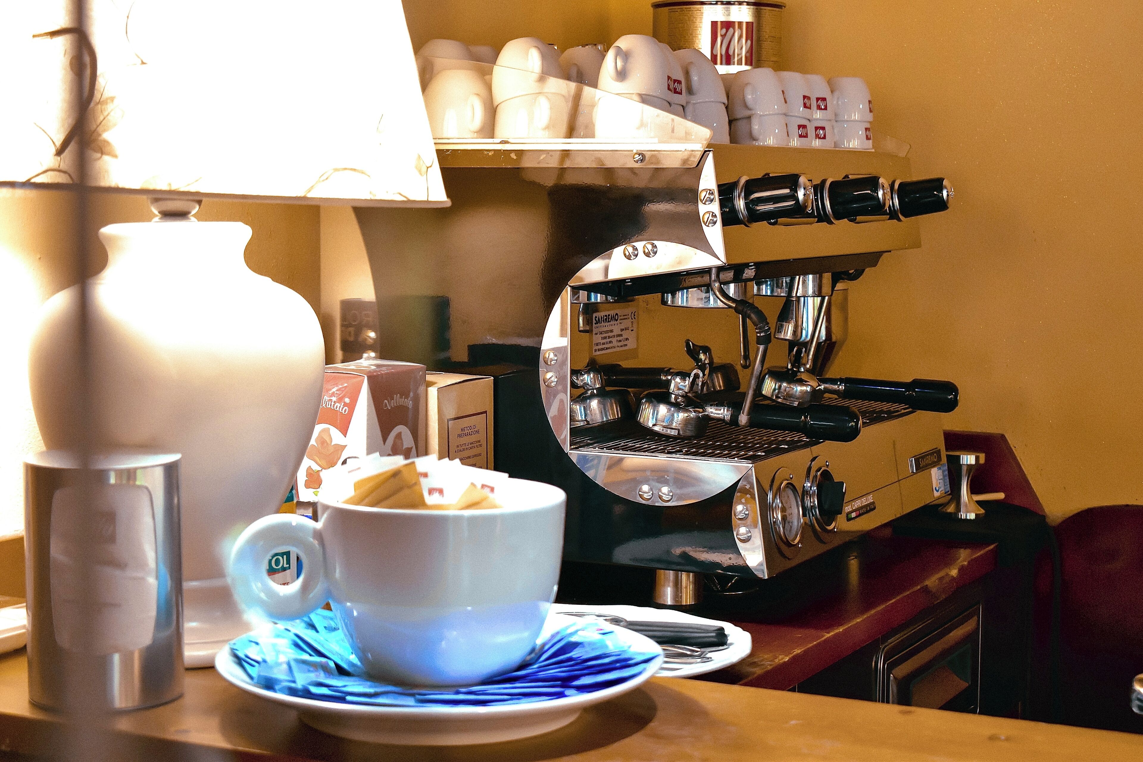 L'intérieur d'un café, avec une machine à café, des tasses et une lampe.