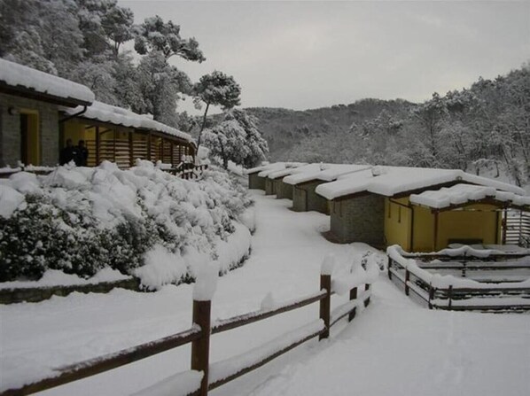 Un albergue cubierto de nieve con varias cabañas, una cerca de madera y un paisaje nevado.