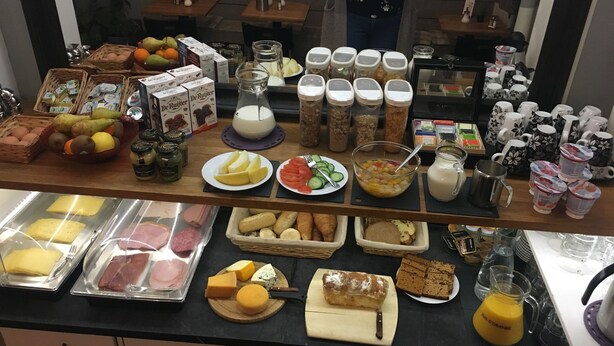 Un bufé de desayuno con diversos alimentos, como frutas, quesos, embutidos y bebidas.