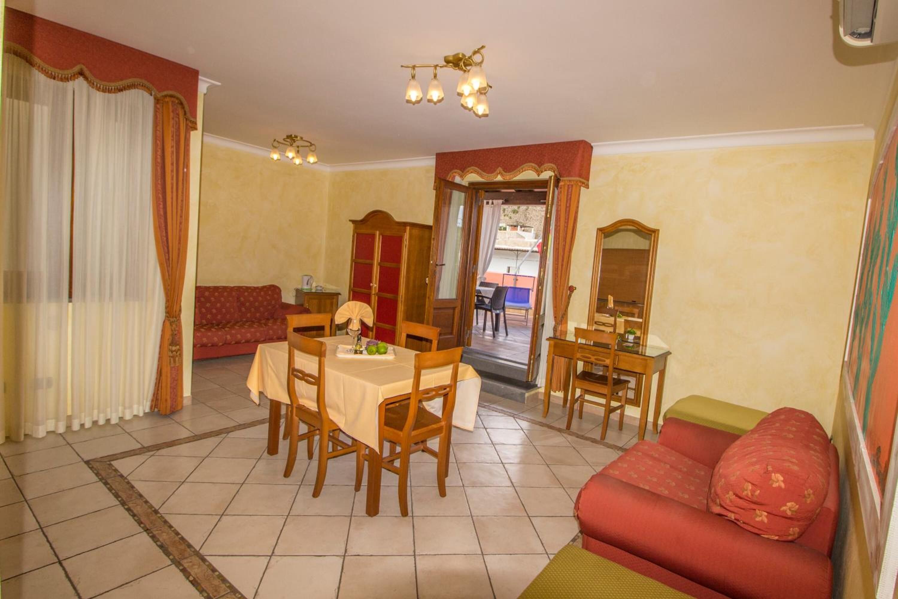 A dining area with a table and chairs, a sofa, and a mirror.