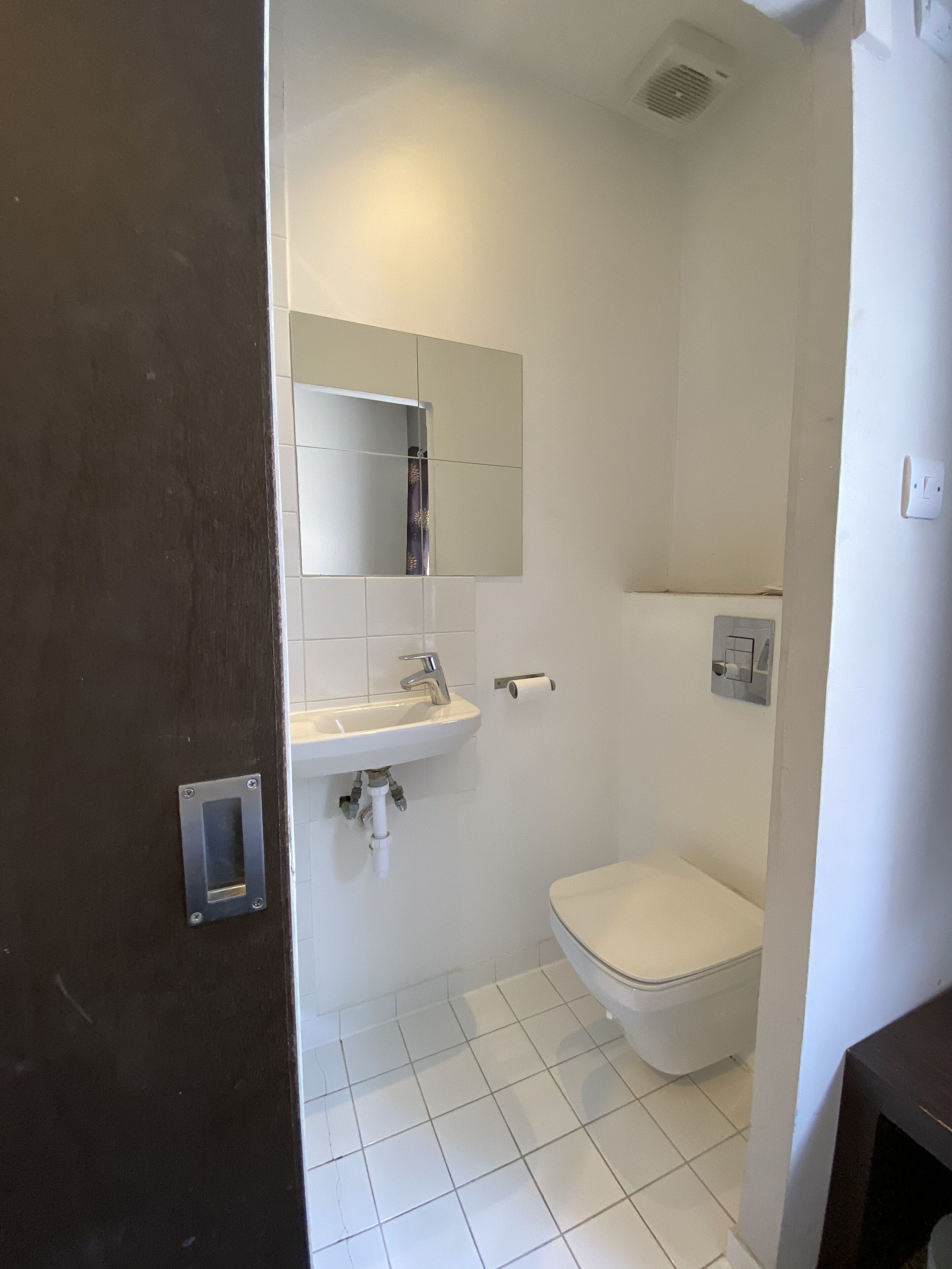 A bathroom with a white sink, mirror, and toilet.