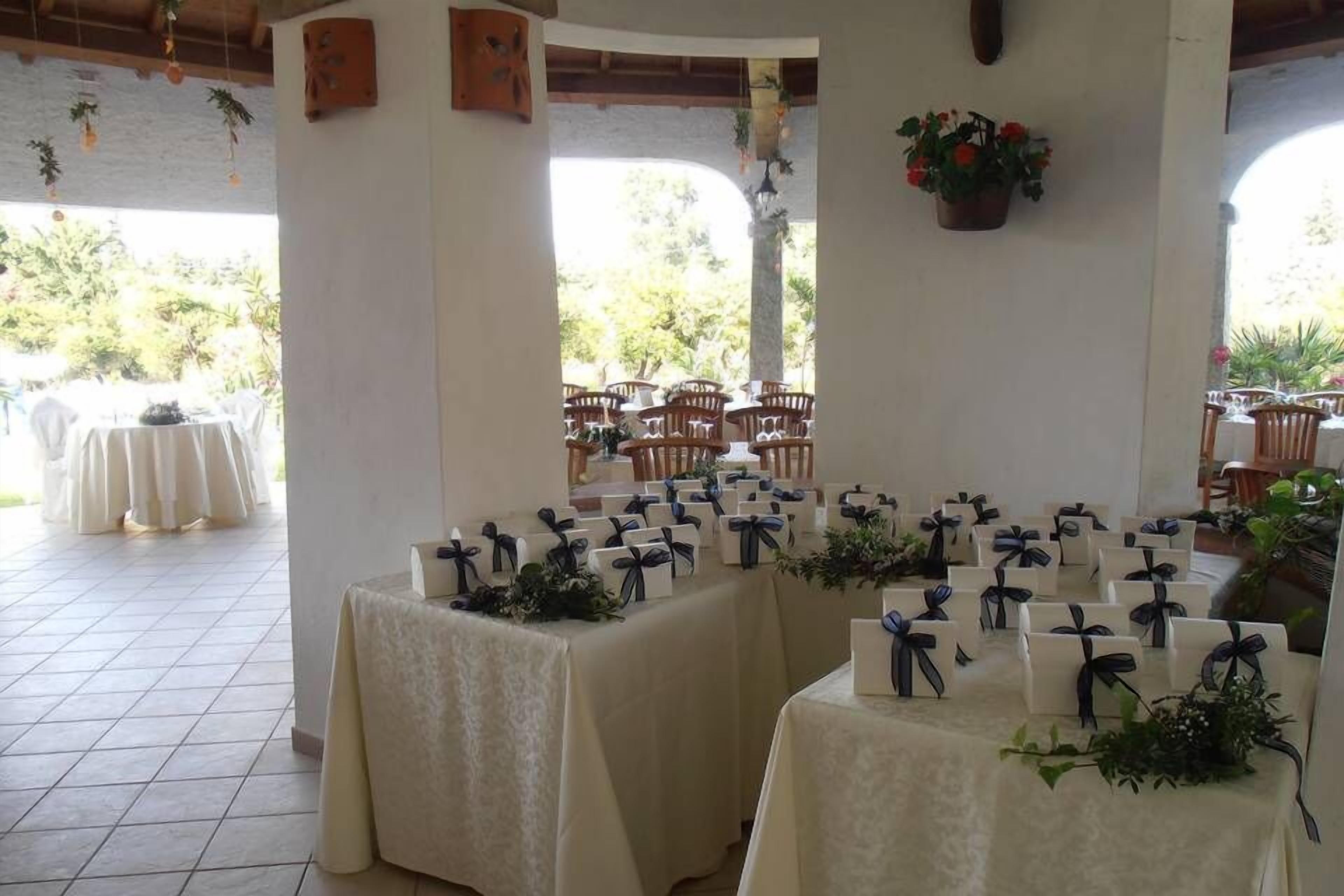 A room with tables set for a wedding, decorated with white tablecloths and blue ribbons.