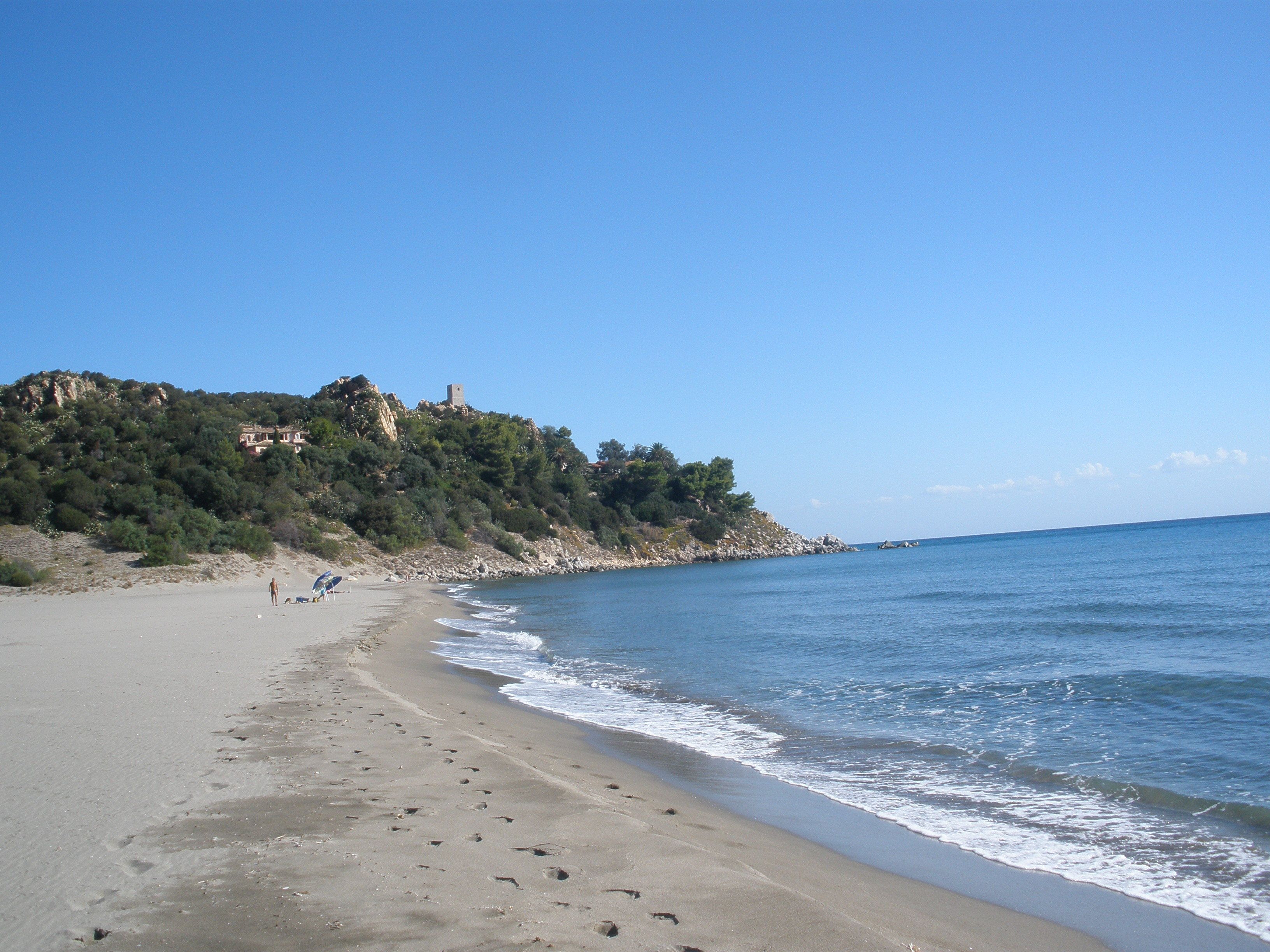 Una spiaggia con una collina rocciosa sullo sfondo.