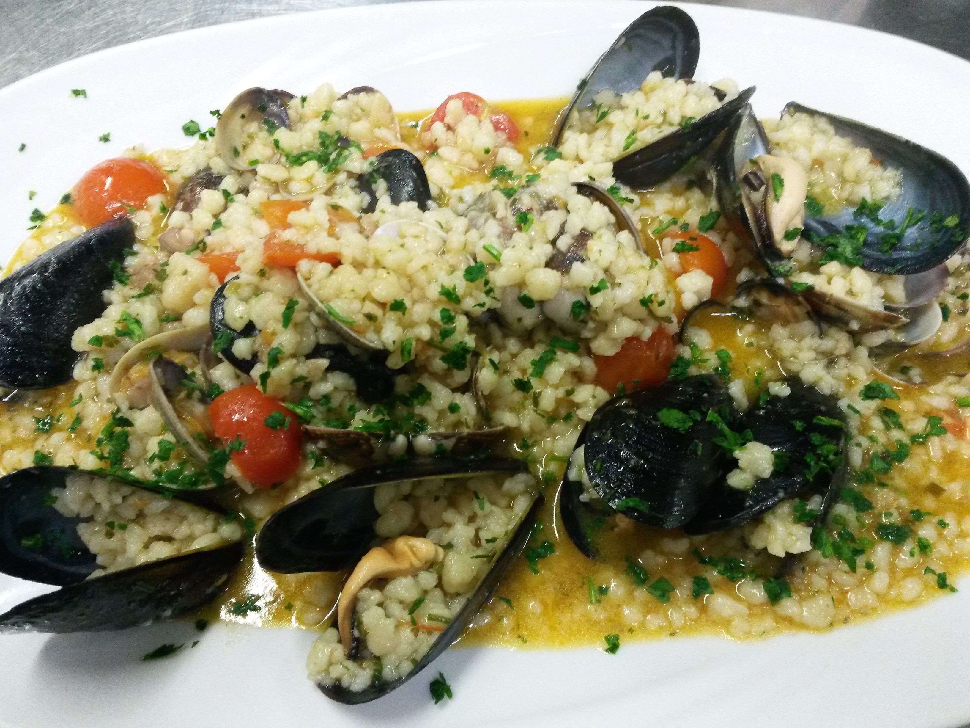 A plate of seafood risotto with mussels and rice, garnished with herbs.