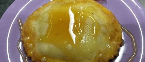 Un postre sobre un plato morado con una rodaja de naranja y almíbar.