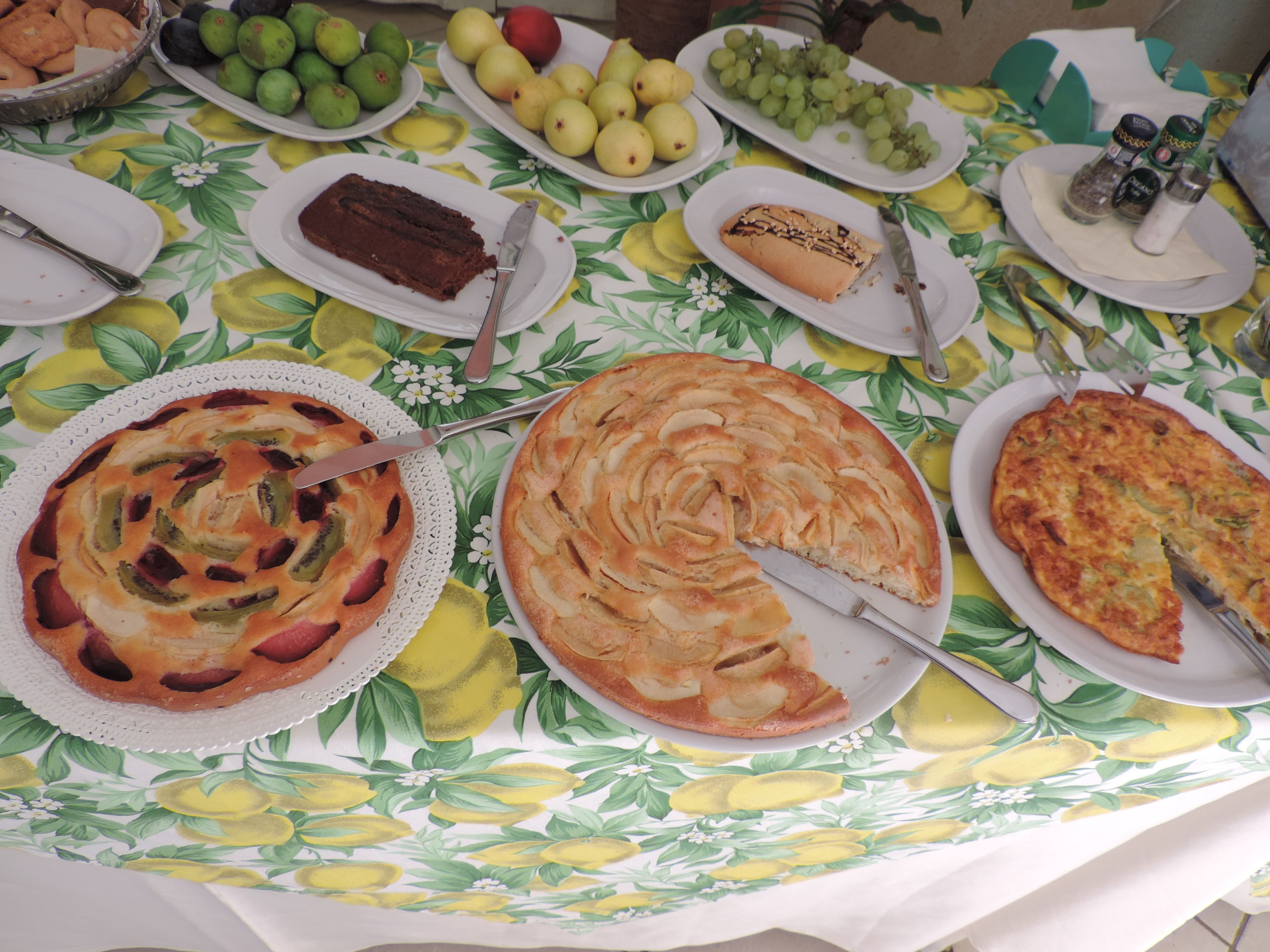 A table with various food items including a pie with a knife, a plate with a slice of cake, and a plate with grapes.