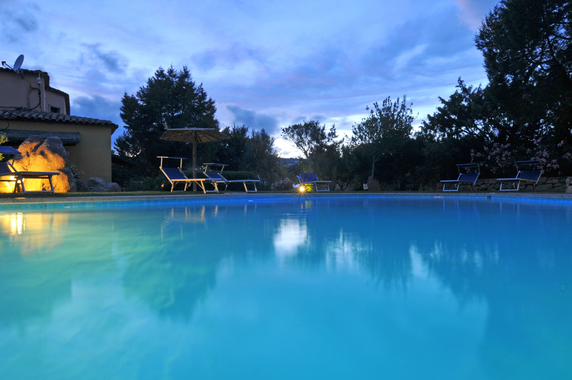A swimming pool with lounge chairs and a building with a satellite dish.