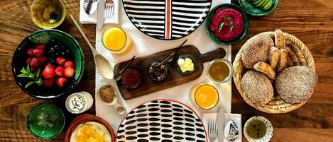 Una escena de desayuno con platos, tazones y utensilios sobre una mesa de madera.