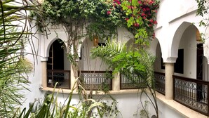 Un patio interior con arcos, una pared blanca y un balcón con barandilla de metal.