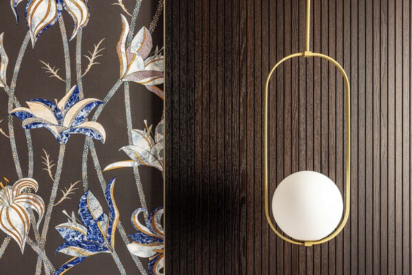A wall with a floral wallpaper pattern and a wooden panel with a gold-framed mirror. - Aramis Deluxe Rooms (Florence)