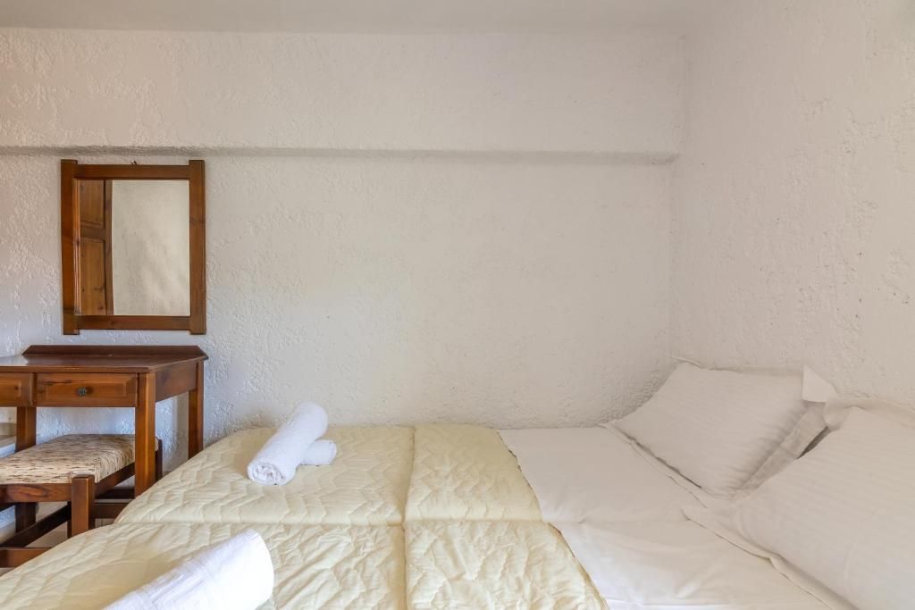 A single bed with a quilted cover, a wooden nightstand with a chair, and a mirror on the wall.