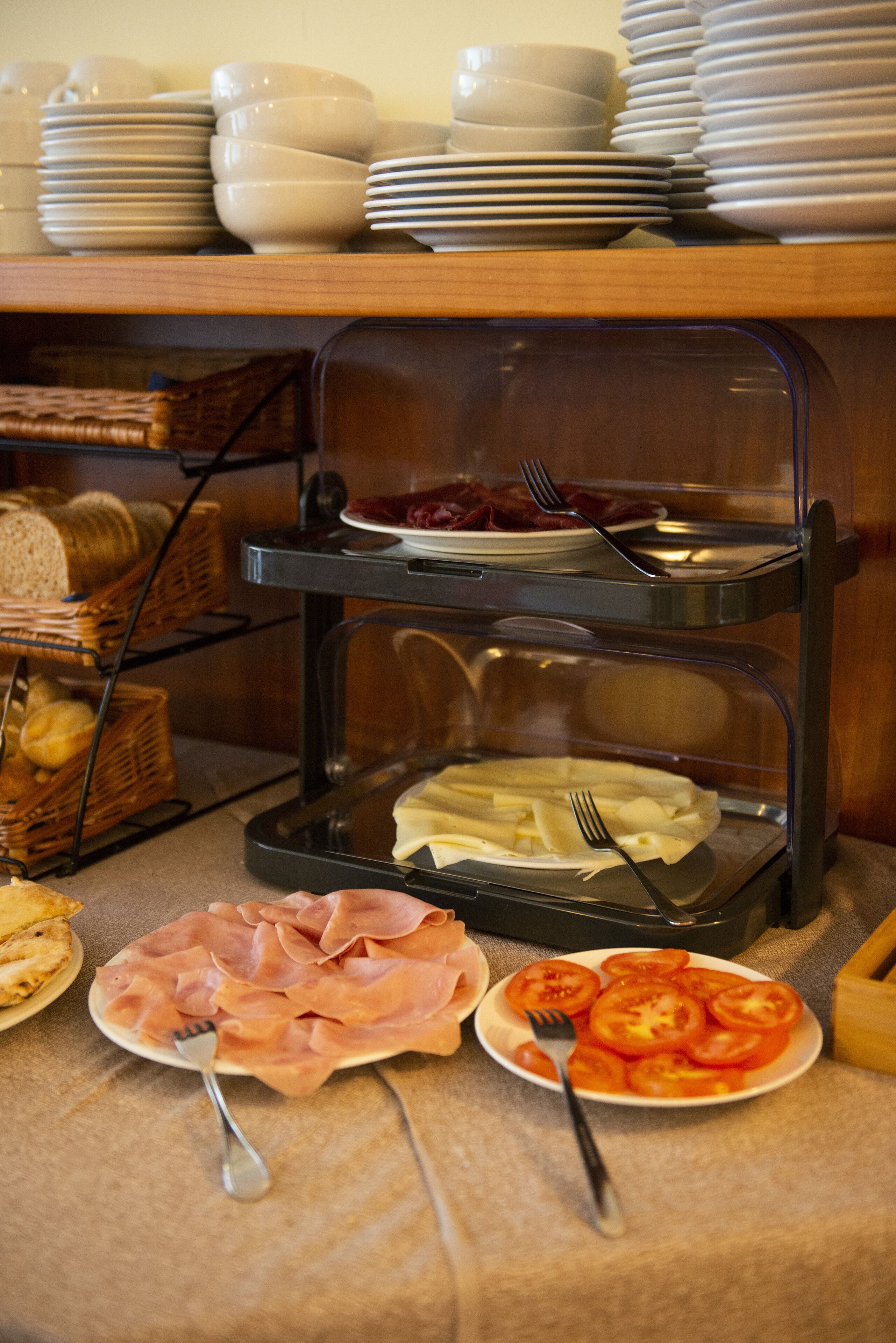 Un buffet con diversi cibi, tra cui pane, prosciutto e pomodori.