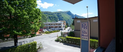 A hotel entrance with a sign for "Park Hotel" and a view of a road leading to a building with parked cars.