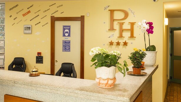 Een receptiebalie met een klok, een bord met daarop 'Welcome' en een bord met 'Private'. Twee potplanten staan op de balie.
