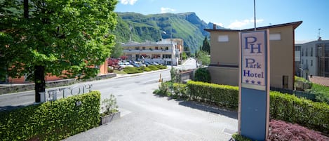 A hotel entrance with a sign for "PH Park Hotel" and a view of a mountain in the background.