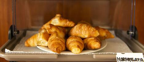 Una vitrina con una variedad de productos de pastelería, incluyendo croissants y muffins, con la etiqueta
