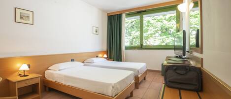 Habitación de hotel con dos camas, un escritorio, una silla, un televisor y una ventana con cortinas.