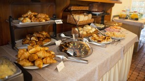 Un buffet proposant une variété d’aliments, notamment des croissants, du pain et des viennoiseries.
