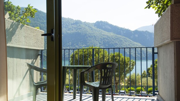 Un balcon avec vue sur un lac et des montagnes, comprenant une table et deux chaises.